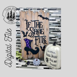 May include: A wooden sign with the text "If the shoe fits" in black lettering. A black witch's shoe with purple accents is attached to the sign. A white pumpkin with the text "Double, double toil and trouble" is in the foreground.