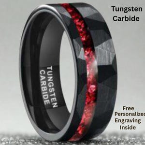 May include: Black tungsten carbide ring with a faceted design and a red inlay. The ring has the words "Tungsten Carbide" printed on the side. The ring is a piece of jewellery.