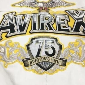 May include: A white ceramic mug with a black handle and the text "But First, Coffee" in a black, handwritten-style font. The mug is on a white surface.