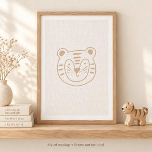 Pu&ograve; includere: Una stampa artistica incorniciata con un'illustrazione a linee color beige di un muso di tigre centrata su uno sfondo testurizzato bianco sporco. La cornice in legno circonda la stampa, che mostra una testa di tigre stilizzata con orecchie tonde.