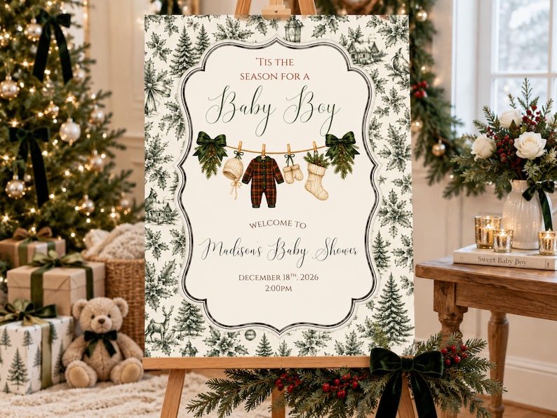 K&ouml;nnte beinhalten: Ein rechteckiges Schild mit cremefarbenem Hintergrund und dunkelgr&uuml;nem botanischem Rand. Der Text lautet 'Tis the season for a Baby Boy', 'Welcome to Madison's Baby Shower', 'December 18th, 2026' und '2:00pm'. Es zeigt eine W&auml;scheleine mit einem Strampler.
