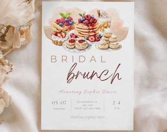 Puede incluir: Una invitación de brunch nupcial al estilo acuarela, con una selección de alimentos para el desayuno como gofres, panqueques y pasteles cubiertos con bayas. El texto de la invitación dice "BRIDAL brunch" e incluye detalles del evento.