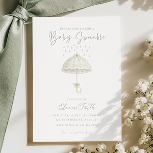 Può includere: Invito Baby Sprinkle con un'illustrazione di ombrello. L'invito presenta il testo "PLEASE JOIN US FOR A Baby Sprinkle" e i dettagli dell'evento. Un nastro verde salvia e fiori bianchi sono sullo sfondo.