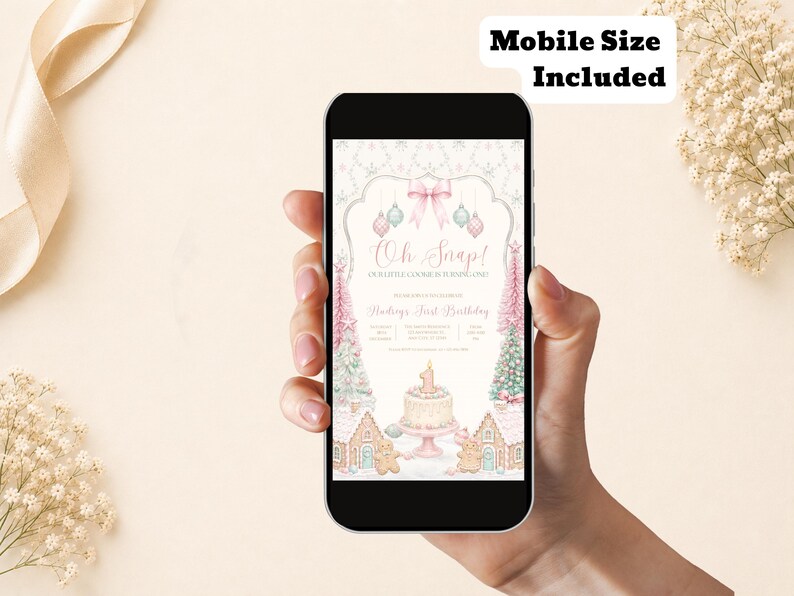 May include: A smartphone displaying a digital birthday invitation with the text Oh Snap! Our Little Cookie Is Turning One! and Hadleys First Birthday. The design features pink and blue ornaments, a cake with a number one candle, and gingerbread houses.