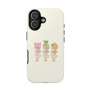 May include: A phone case with an illustration of three small figures in animal-themed hats: a pig, a green vegetable, and a duck. The figures have light skin and ruffled collars. The case is off-white.