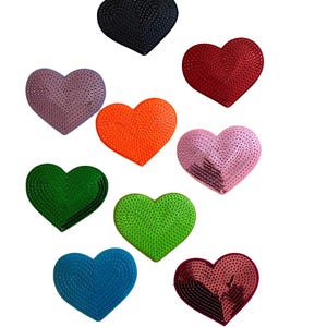 May include: A collection of heart-shaped embellishments in various colors, including black, red, orange, pink, green, and blue. Each heart has a textured surface, creating a visually appealing design. These decorative hearts are suitable for crafts and embellishments.