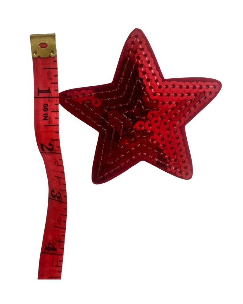 May include: A red sequined star with a 10 cm measurement next to it. The star is a vibrant red colour and is covered in small, shiny sequins. The measuring tape is red with white markings.