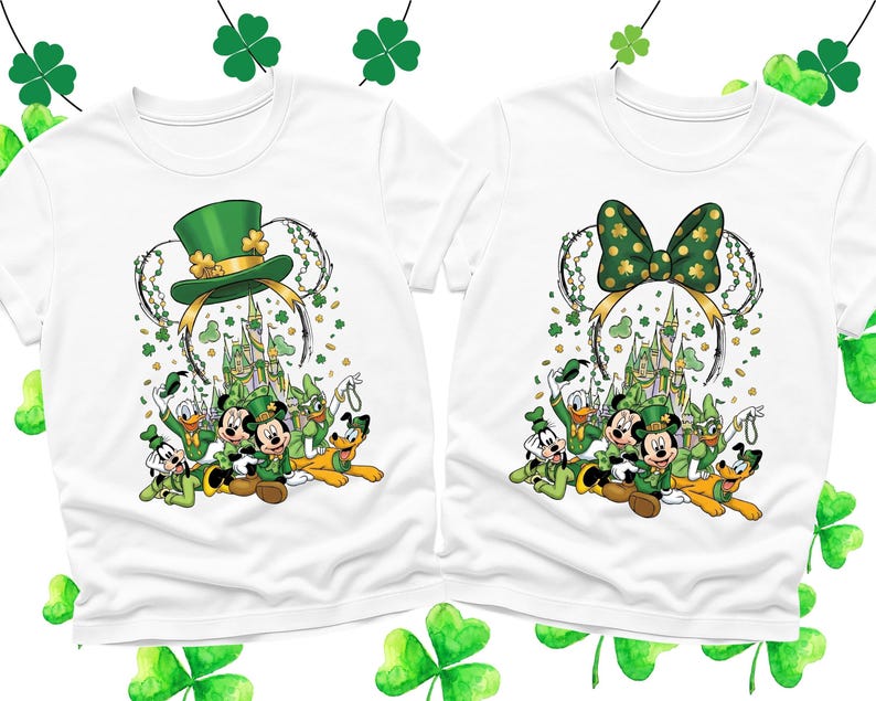 May include: Two white t-shirts featuring a St. Patrick's Day design. One shirt has a green leprechaun hat and the other a green bow, both with Mickey Mouse ears. The shirts also feature Disney characters and a castle.