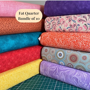 May include: A Fat Quarter Bundle of 10 fabric pieces stacked in two columns. The textiles feature various patterns including floral, paisley, swirl, and geometric designs in colors of pink, orange, teal, red, yellow, purple, and blue.