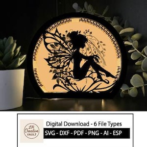 Peut inclure: Une silhouette noire d'une fée avec des ailes détaillées et des accents floraux, dans un cadre circulaire. Le design est éclairé par l'arrière, créant une lueur chaleureuse. Le texte "Digital Download - 6 File Types" est inclus.