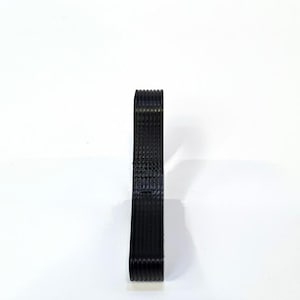 May include: A stack of black, woven ribbon stands upright against a white background. The ribbon appears to be made of a textured material, with visible horizontal lines. The edges of the ribbon are neatly aligned, creating a clean, organized appearance.