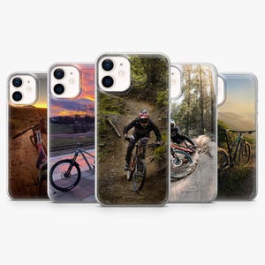 Op de afbeelding: Een verzameling van vijf telefoonhoesjes met mountainbike-scènes. De hoesjes tonen afbeeldingen van fietsers op paden, met levendige zonsondergang- en bosachtergronden. De hoesjes zijn ontworpen voor een smartphone.