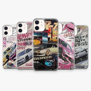 May include: A collection of five phone cases featuring Japanese car magazine-style designs. Each case showcases colorful car illustrations and Japanese text, with a retro aesthetic. The cases are designed to fit a smartphone.