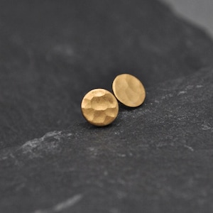 Könnte beinhalten: Ein Paar goldfarbene, gehämmerte runde Ohrstecker.
