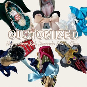 May include: A collection of six customized pointe shoes decorated as Nutcracker characters, featuring ribbons, lace, sequins, and miniature props. The text CUSTOMIZED Nutcracker Role Keepsake Pointe Shoe is centered among the shoes, which include red, green, blue, and black designs.
