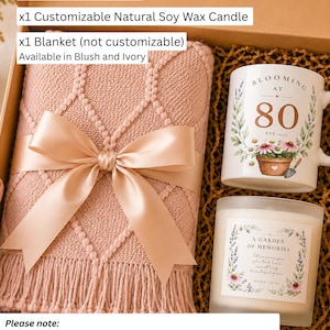 May include: A gift set in a box containing a blush pink knit blanket with a satin ribbon, a white ceramic mug with floral graphics and the text 'BLOOMING AT 80 EST. 1945', and a glass jar candle with a label reading 'A GARDEN OF MEMORIES'.