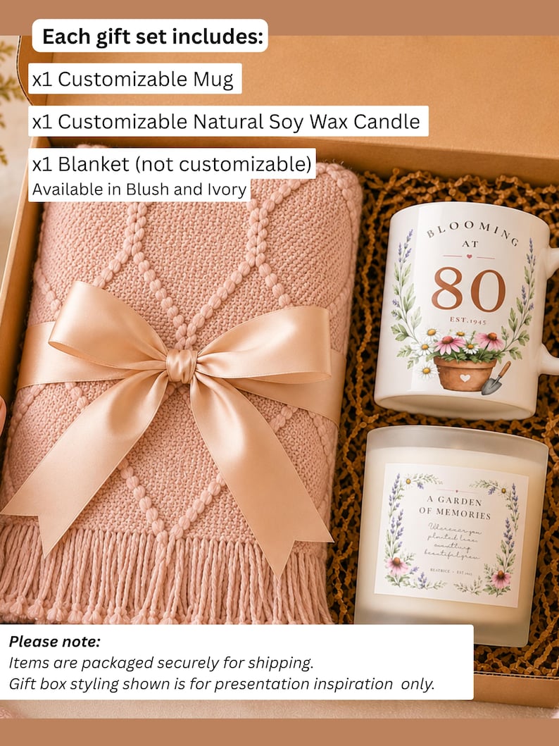 May include: A gift set in a box containing a blush pink knit blanket with a satin ribbon, a white ceramic mug with floral graphics and the text 'BLOOMING AT 80 EST. 1945', and a glass jar candle with a label reading 'A GARDEN OF MEMORIES'.