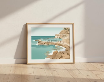 May include: Framed art print featuring a coastal scene with a turquoise ocean and a swimming pool built into the rocks. The artwork has a minimalist style with a light brown wooden frame, leaning against a white wall on a wooden floor.