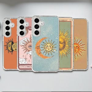 May include: A collection of five phone cases with tarot-inspired designs. Each case features a different illustration, including sun and moon motifs, in shades of orange, pink, blue, and brown. The cases are displayed on a white surface.