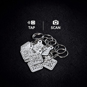 May include: A collection of silver-toned square keychains featuring a black and white QR code design on each face. Above the keychains, the text TAP with a signal icon and SCAN with a camera icon are displayed in white against a dark background.