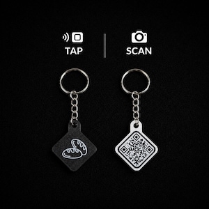 May include: Two square keychains with metal rings and chains. The left keychain is black with a white bread icon, labeled TAP with a signal icon. The right keychain is white with a black QR code, labeled SCAN with a camera icon above it.