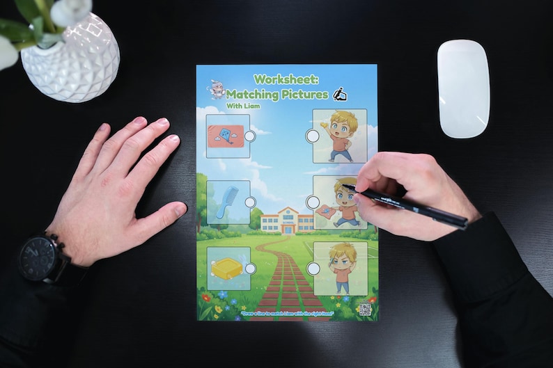 May include: A worksheet titled "Matching Pictures" with illustrations and the name "Liam". The worksheet is being completed with a black pen. A white mouse and a white vase with flowers are also visible.