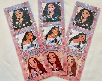 Puede incluir: Tres marcadores de libros con ilustraciones de una mujer con cabello largo en varios estilos. Los marcadores tienen un diseño floral rosa con un marco en forma de ventana alrededor de las ilustraciones. Las ilustraciones son de estilo caricatura.