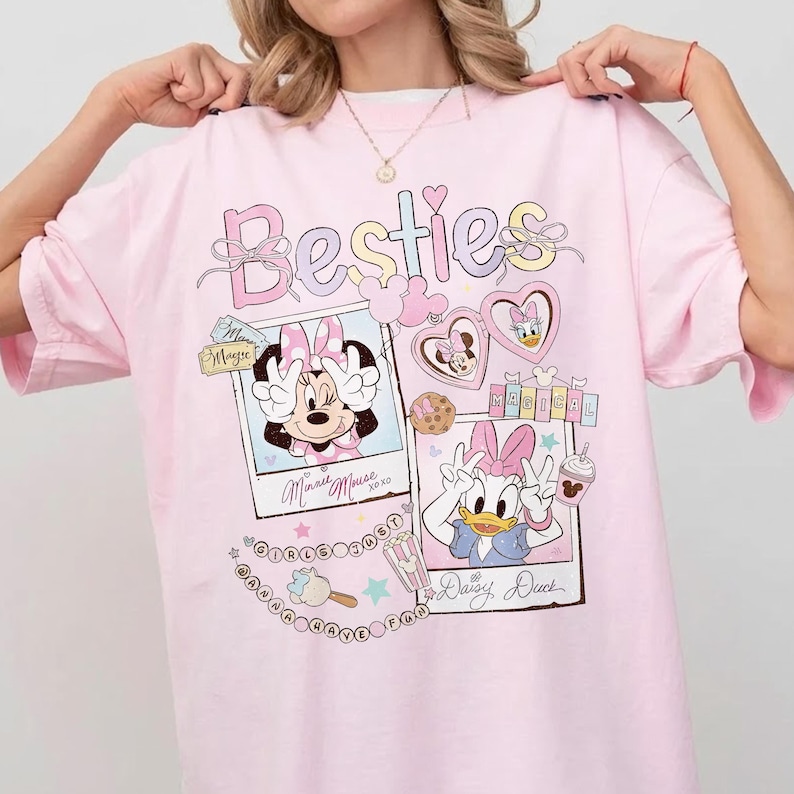 Peut inclure: T-shirt rose clair avec le mot "Besties" en couleurs pastel. Le t-shirt pr&eacute;sente Minnie Mouse et Daisy Duck dans des cadres de style polaroid, avec des c&oelig;urs, des biscuits et de la cr&egrave;me glac&eacute;e. Le t-shirt a une coupe ample.