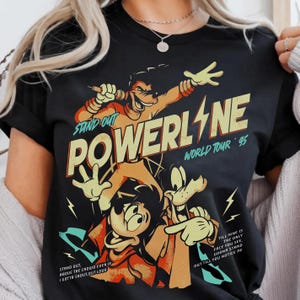 May include: Black t-shirt featuring a cartoon graphic of Powerline from the movie A Goofy Movie. The design includes the text "POWERLINE WORLD TOUR '95" and song lyrics. The characters are in shades of orange, yellow, and black.