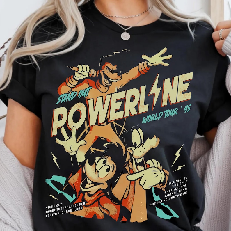 May include: Black t-shirt featuring a cartoon graphic of Powerline from the movie A Goofy Movie. The design includes the text "POWERLINE WORLD TOUR '95" and song lyrics. The characters are in shades of orange, yellow, and black.
