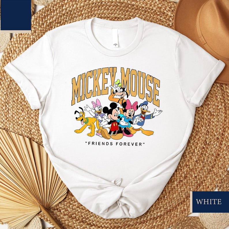 May include: White crew neck t-shirt with a graphic of Mickey Mouse and friends, including Donald Duck, Goofy, and Minnie Mouse. The text "MICKEY MOUSE" is arched above the characters, with "FRIENDS FOREVER" below.