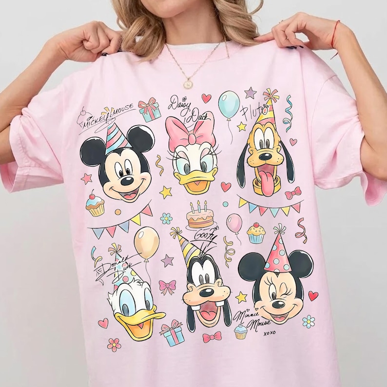 May include: Pink t-shirt featuring Mickey Mouse, Minnie Mouse, Donald Duck, Daisy Duck, Goofy, and Pluto, all wearing party hats. The shirt includes the text "Mickey Mouse" and "Daisy Duck" in cursive, along with balloons, cupcakes, and confetti.