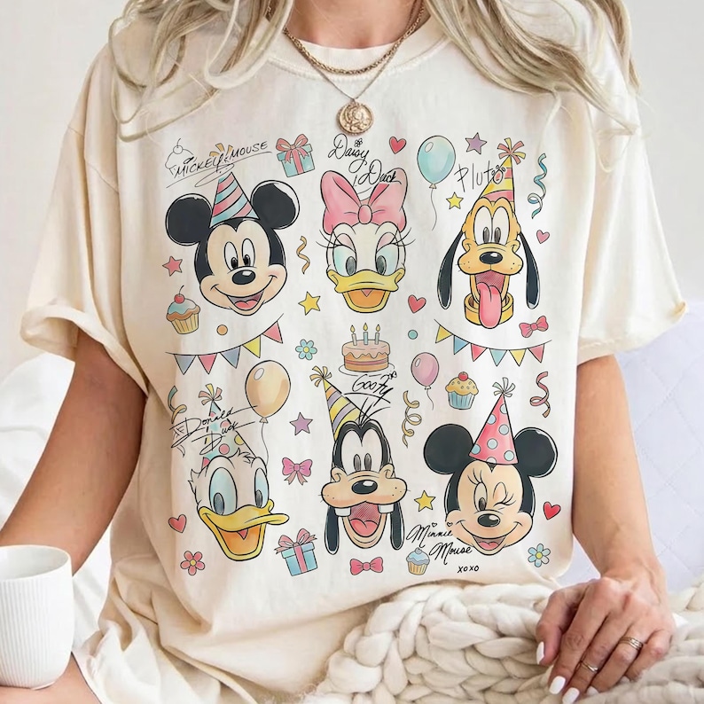 May include: Cream-colored t-shirt featuring Mickey Mouse, Daisy Duck, Pluto, Donald Duck, Goofy, and Minnie Mouse. The design includes birthday party elements like balloons, confetti, and cake. Text includes "Mickey Mouse", "Daisy Duck", "Goofy", and "Minnie Mouse xoxo".