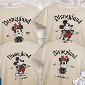 May include: Four cream-coloured t-shirts with Disneyland graphics. Each shirt features a different Mickey or Minnie Mouse design, with the text "Disneyland" and "est. 1955". Two shirts also say "California".