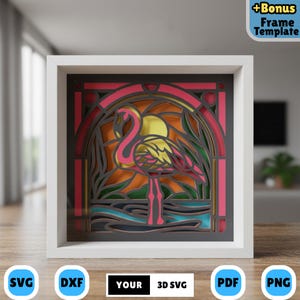 May include: A layered paper art piece featuring a pink flamingo in a stained-glass style design. The artwork is set against a sunset backdrop with a yellow sun and green foliage. The piece is framed in a white square frame. Text includes "+Bonus Frame Template", "SVG", "DXF", "YOUR 3D SVG", "PDF", and "PNG".