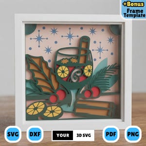 Peut inclure: Un artisanat en papier superposé dans un cadre blanc représentant un verre de vin chaud avec un bâton de cannelle, des tranches d'orange et du houx. Fond rose clair avec des étoiles bleues. Texte : "+Bonus Frame Template" et "YOUR 3D SVG".
