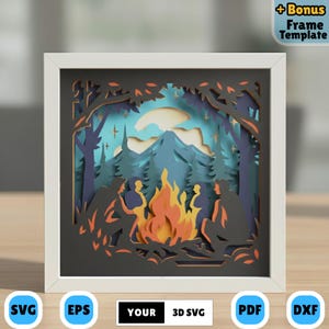 May include: A framed 3D paper art piece depicting a campfire scene. The artwork features silhouetted figures around a bright orange and yellow fire, with a mountain and forest backdrop. The frame is white, and the artwork includes the text "YOUR 3D SVG".