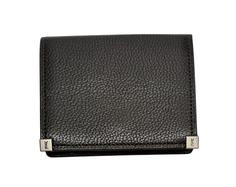Peut inclure: Un portefeuille en cuir noir avec une surface textur&eacute;e. Le portefeuille de forme rectangulaire est orn&eacute; de coins en m&eacute;tal argent&eacute;. Le portefeuille est ferm&eacute; et semble neuf.