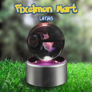 Op de afbeelding: Een heldere, bolvormige display met een roze en paars personage erin. De display staat op een zilveren voet met een paarse gloed. De tekst "Pixelmon Mart" en "Latias" zijn zichtbaar boven de bol. De achtergrond is wazig groen.