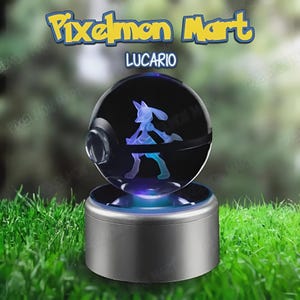 May include: A silver-based display featuring a glowing Lucario figure within a clear sphere. The sphere is part of a Pixelmon Mart product, with the name "Lucario" displayed. The base emits blue light. The background is blurred.