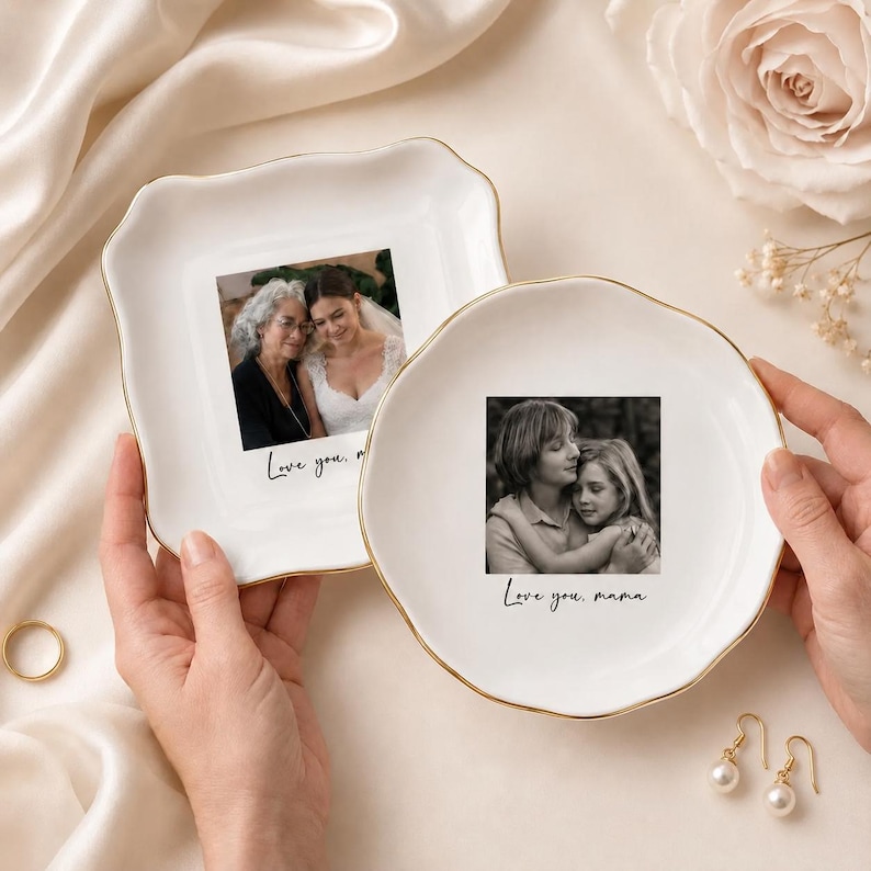 May include: Two white ceramic trinket dishes with gold rims, each featuring a black and white photograph. One dish has a square shape, the other is round. The text "Love you, mama" is written on the round dish.