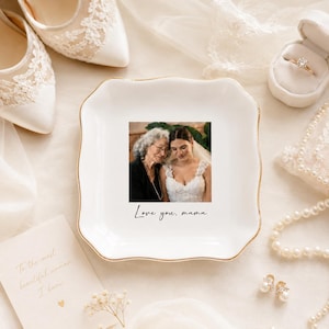 May include: A white ceramic trinket dish with a gold rim features a photo of a bride and her mother, with the text "Love you, mama." The dish is surrounded by wedding accessories, including shoes and a ring box.