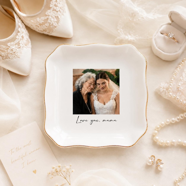 May include: A white ceramic trinket dish with a gold rim features a photo of a bride and her mother, with the text "Love you, mama." The dish is surrounded by wedding accessories, including shoes and a ring box.