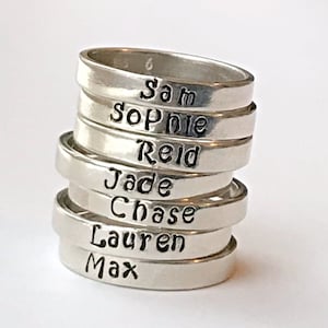 May include: Stack of silver rings with names engraved on each band: Sam, Sophie, Reid, Jade, Chase, Lauren, Max.