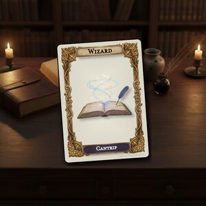 May include: A rectangular game card featuring an ornate gold frame with the word WIZARD at the top and CANTRIP at the bottom. The center illustration shows an open book with a blue quill pen writing, surrounded by swirling blue magical energy.