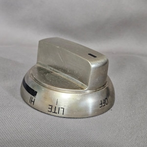May include: A brushed metal stove knob with a rectangular top and a circular base. The base has markings for "HI", "LITE", and "OFF". A black line indicates the current setting.