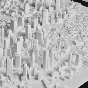 May include: A detailed, white 3D model of a city, showcasing a dense urban landscape with numerous skyscrapers and buildings of varying heights. The model highlights the city's architecture and layout.