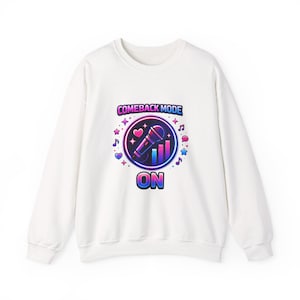 Könnte beinhalten: Weißes Sweatshirt mit einem farbenfrohen Aufdruck mit der Aufschrift "COMEBACK MODE ON". Die Grafik zeigt ein Mikrofon, Noten und Sterne in Pink-, Blau- und Lilatönen. Ein lässiges, bequemes Oberteil.