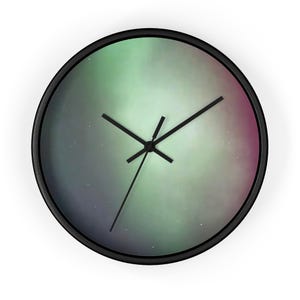 May include: Round wall clock with a black frame. The clock face features a colorful, abstract design with shades of green, purple, and pink, resembling the aurora borealis. Black clock hands indicate the time.
