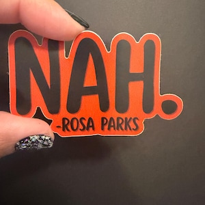 May include: A sticker with the word "NAH" in bold black letters on a bright orange background. Below the word "NAH" is the text "-ROSA PARKS" in black. The sticker has a white border and a black dot at the end of the word "NAH."